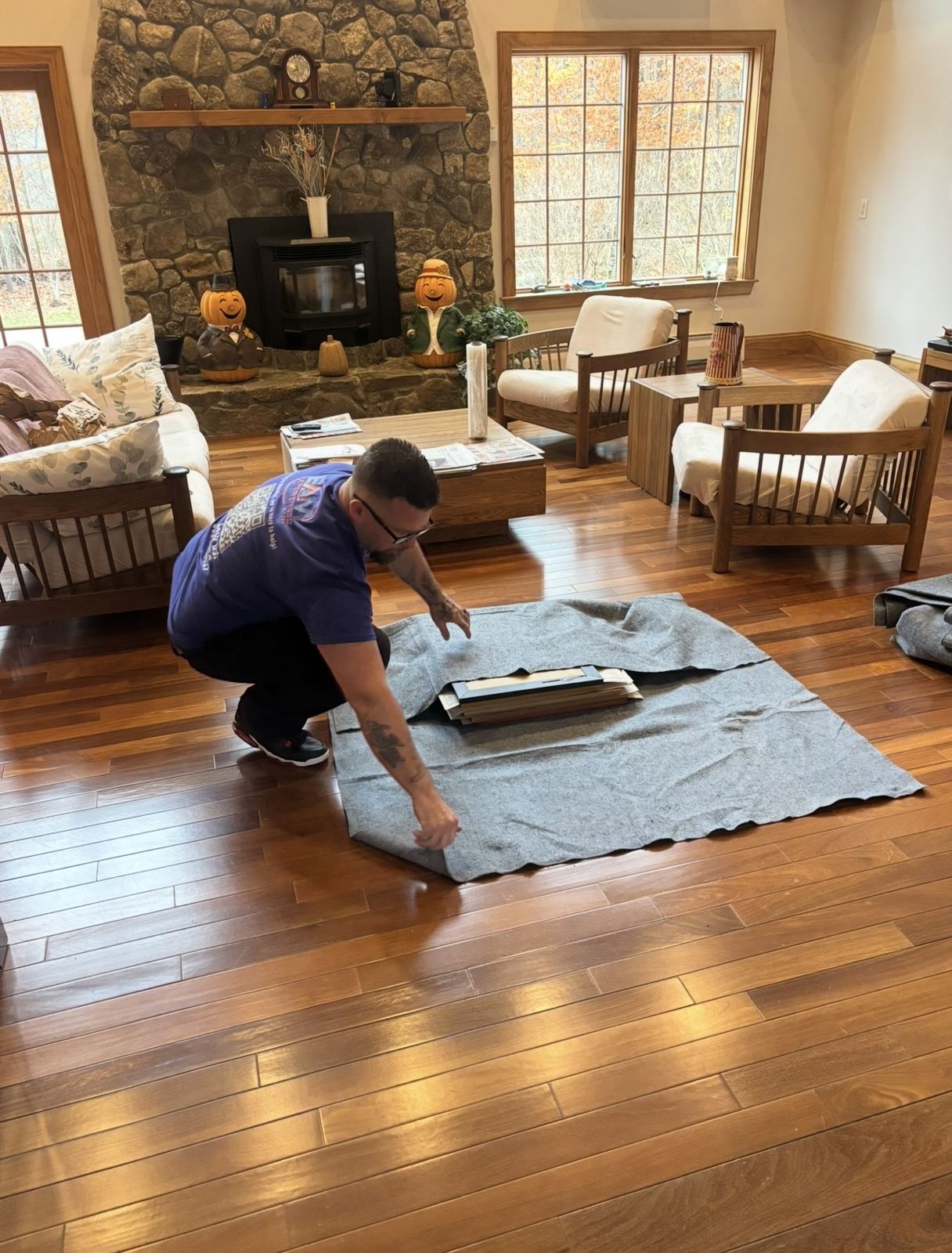 EAM Moving crew member laying a moving blanket over hardwood floors during a full-service packing job in Meredith, New Hampshire